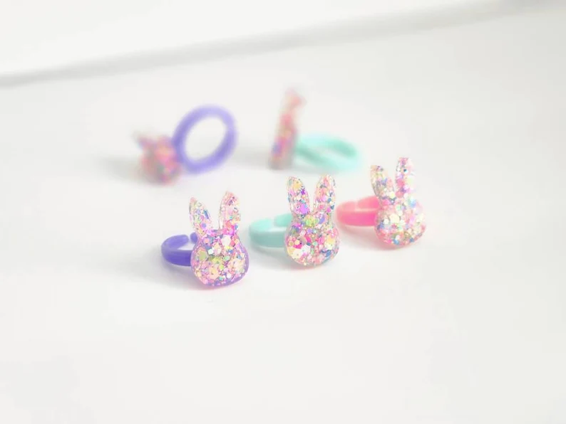 Glittery bunny-shaped rings in pastel colors, perfect for Easter Party Favors Kids will love in baskets or egg hunts.