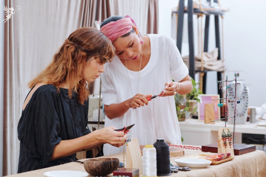 two ladies at a work table discussing crafting