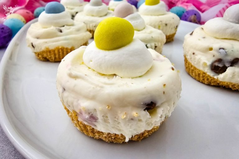 Macro shot of a Mini Egg Cheesecake recipe showing the buttery graham cracker crust and smooth, candy-filled cream cheese layer.