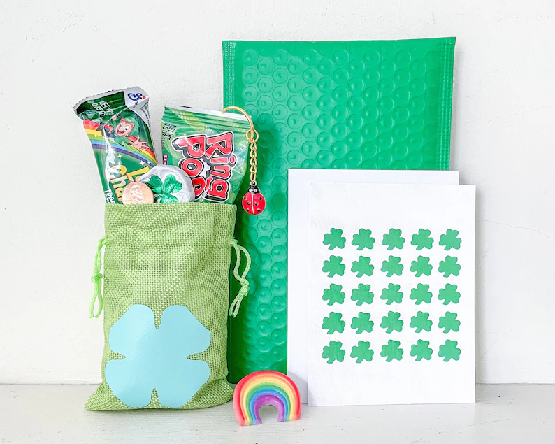A green burlap bag filled with themed candy and toys, featuring a large light blue shamrock for vibrant St. Patrick's Day favors.