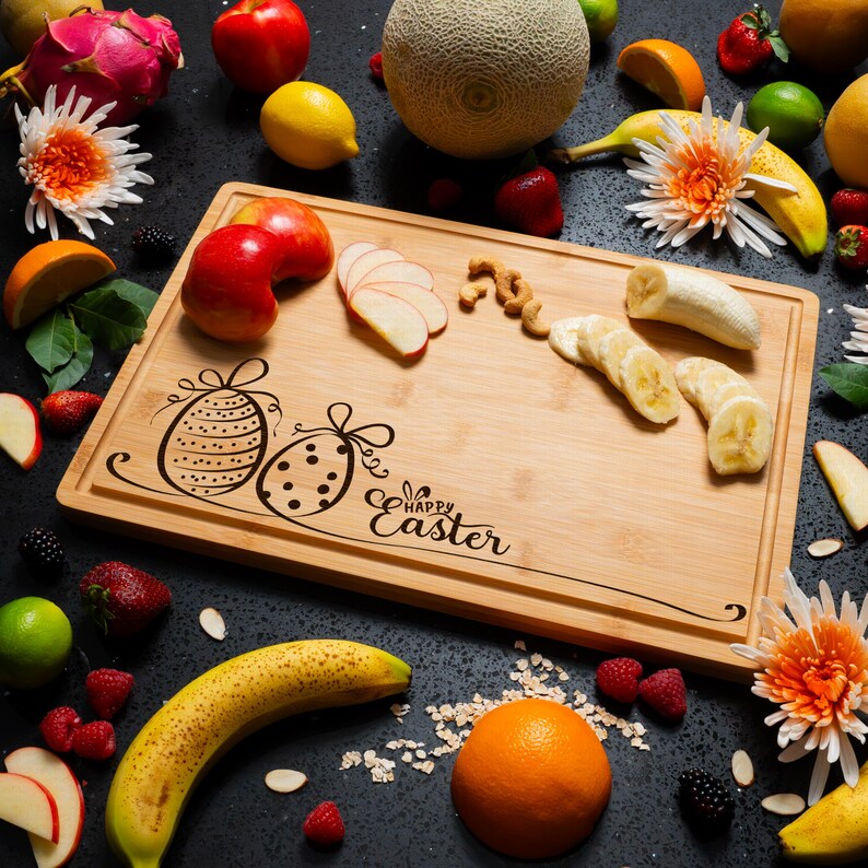 Personalized wooden cutting board with engraved eggs and "Happy Easter" text, surrounded by fruit. A thoughtful Easter Hostess Gift.