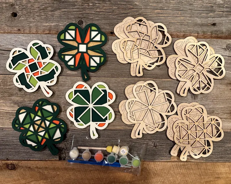 Wooden shamrock craft kits with geometric patterns, including paint pots and brushes, perfect for creative and artistic St. Patrick's Day favors.