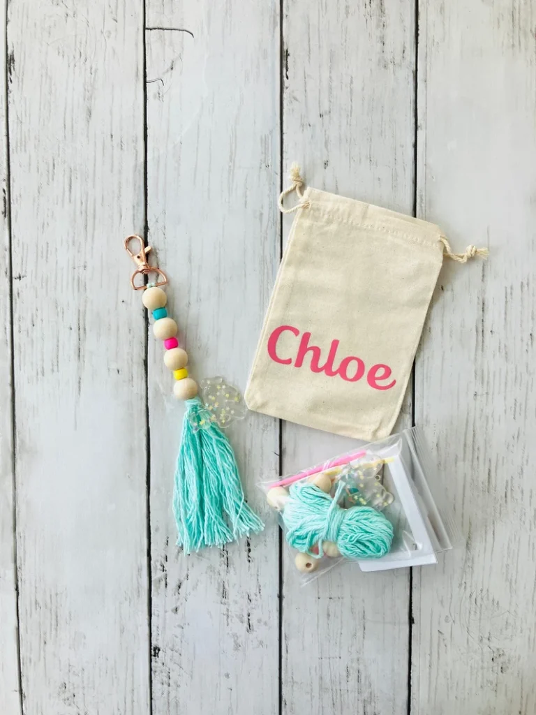 A personalized canvas bag containing a wooden bead tassel keychain and a DIY assembly kit for sleepover party favors. Etsy