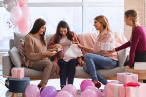 ladies sitting on a couch offering gifts to a pregnant mother baby shower scene