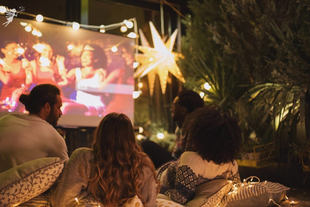 outdoor cinema set up with young adults watching a movie in a garden