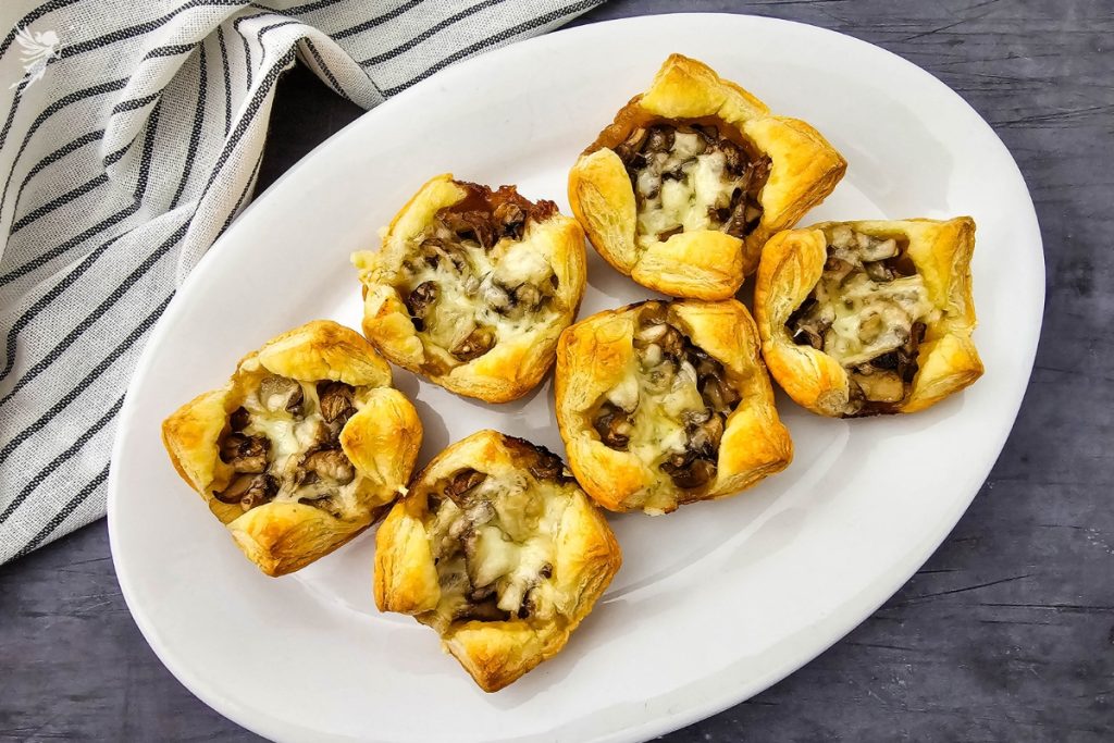 Golden brown Mushroom Puff Pastry Bites served on a white platter, an easy appetizer for holiday parties and gatherings.