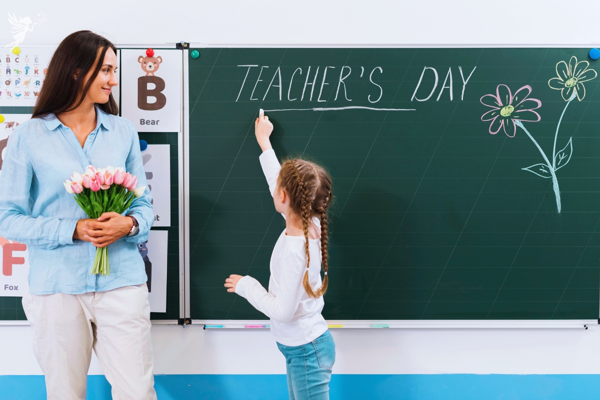 female teacher holding flowers with little girl writing teachers day on a blackboard with chalk