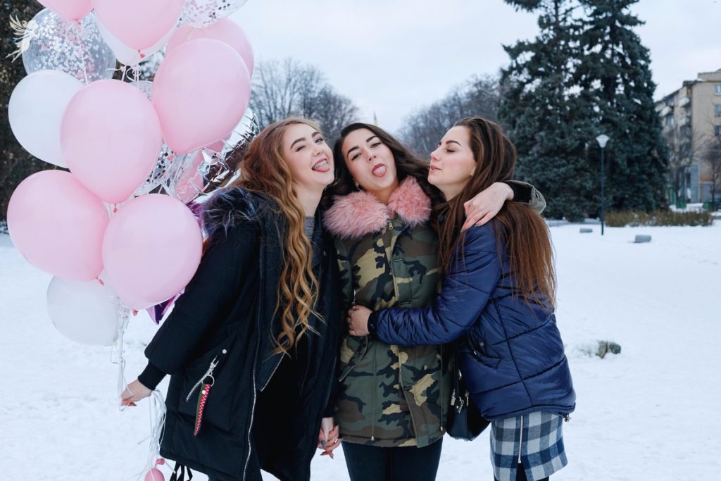 three teenage gifrl in the snow with pink and white balloons