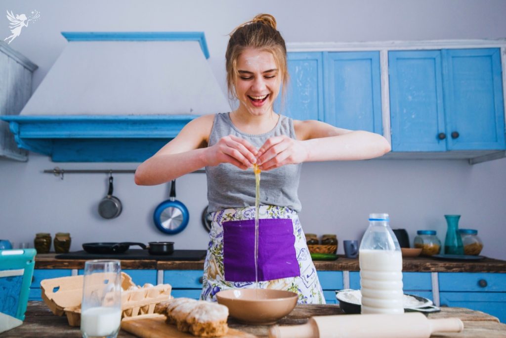 a teen girl excitedly breakingan agg into a bowl