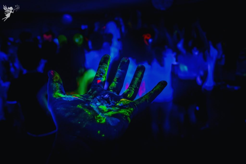 a glowing neon green hand in front of a neon paerty scene