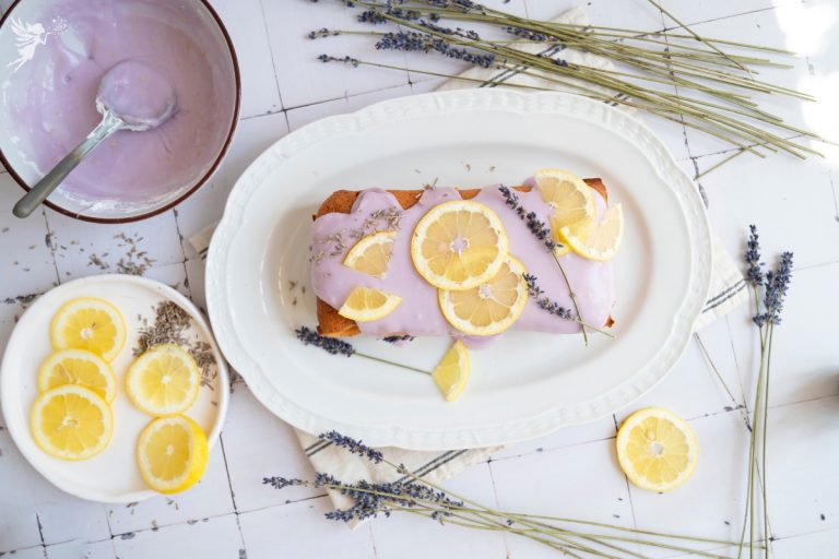 Flat lay of a homemade Lemon Lavender Pound Cake on a platter, featuring floral icing, lemon slices, and culinary lavender garnish.