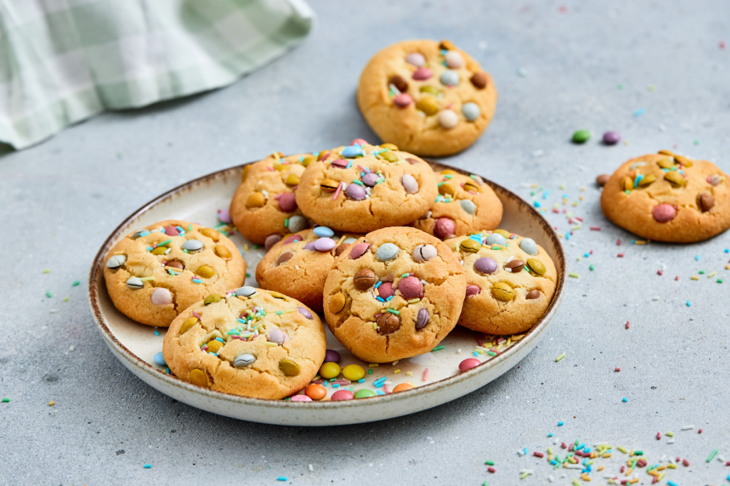 A stack of colorful chocolate-covered candy treats on a plate, the final delicious result of this Easter cookie recipe.