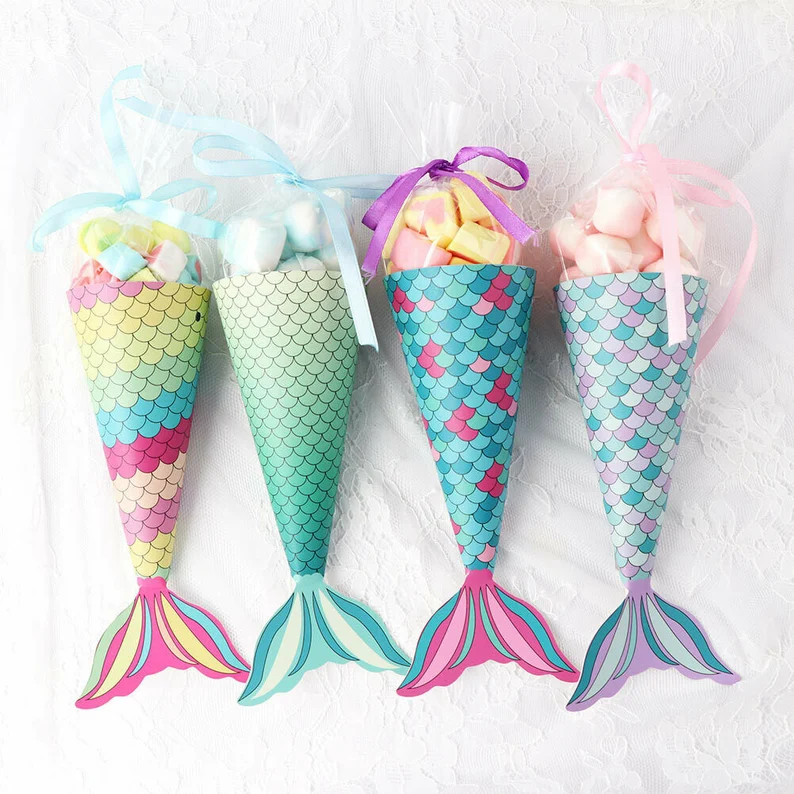 Colorful mermaid tail candy cones filled with marshmallows and treats, wrapped in cellophane with ribbons, make adorable mermaid party favors for celebrations.
