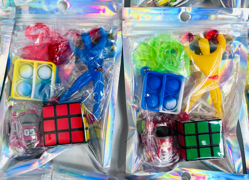 Holographic goodie bags filled with fidget toys, pop-its, Rubik's cubes, and stretchy figures, fun tween teen boy party favors for any birthday party.