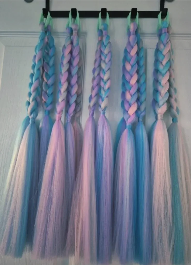 Pastel braided hair extensions in turquoise, pink, and purple ombre shades hanging on hooks make enchanting mermaid party favors for dress-up play.