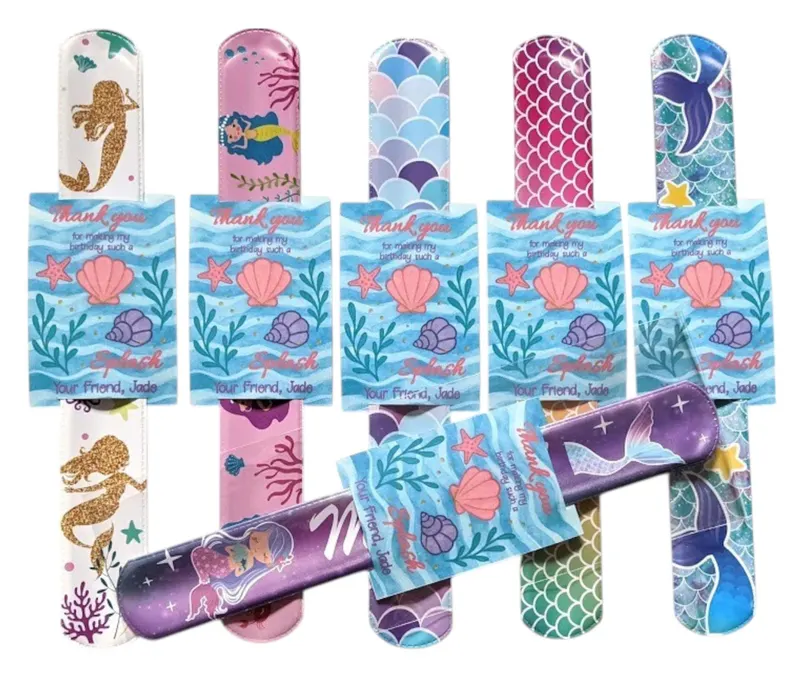 Colorful mermaid slap bracelets with scale patterns and glitter designs attached to ocean-themed thank you cards, perfect mermaid party favors for celebrations.