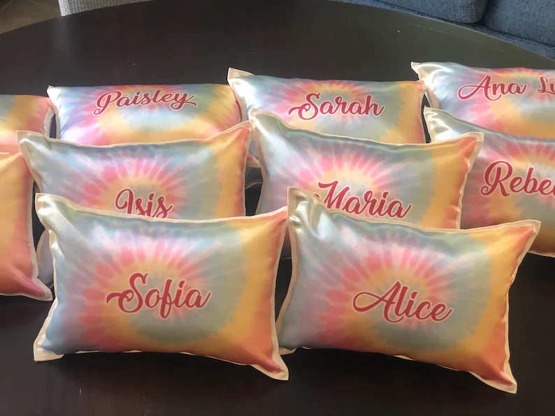 Personalized tie-dye satin pillowcases with custom names in pink script, unique sleepover party favors for girls' slumber celebrations.