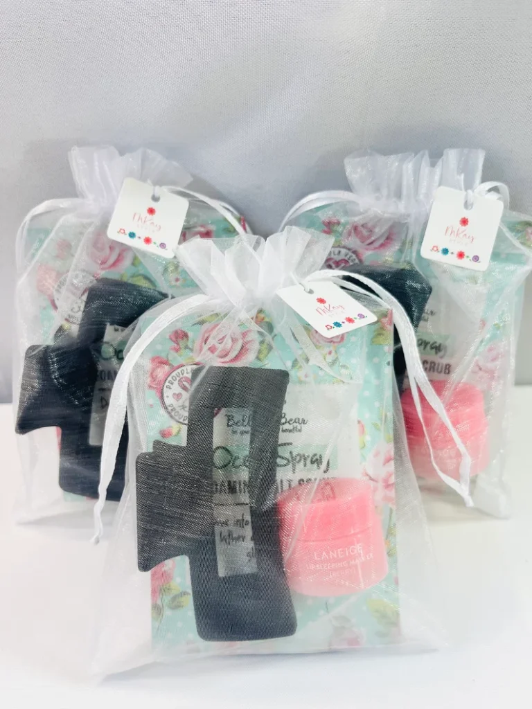 Organza bags featuring rose-print packaging, a black hair claw clip, and a pink Laneige lip mask for sleepover party favors.