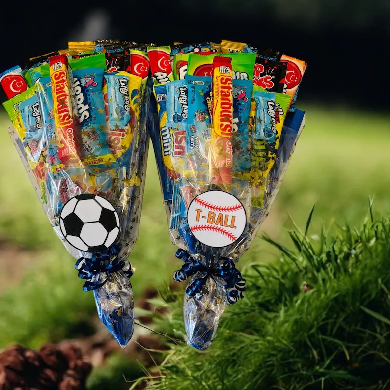 Soccer and T-ball themed candy bouquet cones packed with Starburst, Laffy Taffy, and assorted treats tied with blue ribbon, sporty tween teen boy party favors.