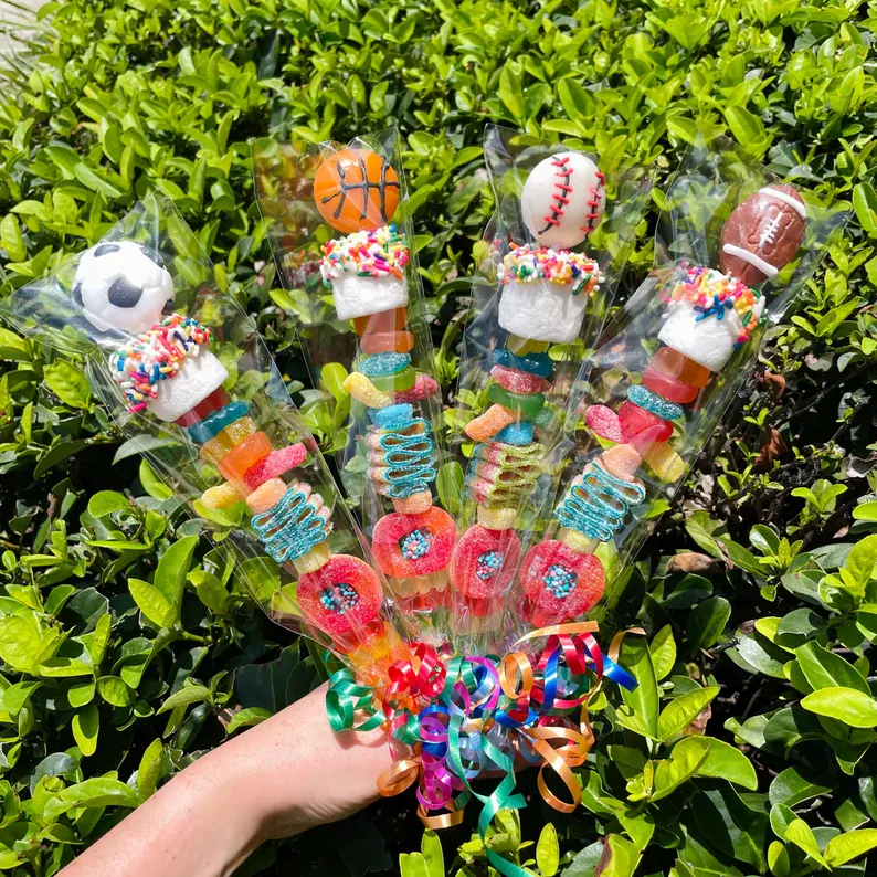 Sports candy kabobs topped with soccer, basketball, baseball, and football shaped treats with gummy candies, colorful tween teen boy party favors for sports themed parties.