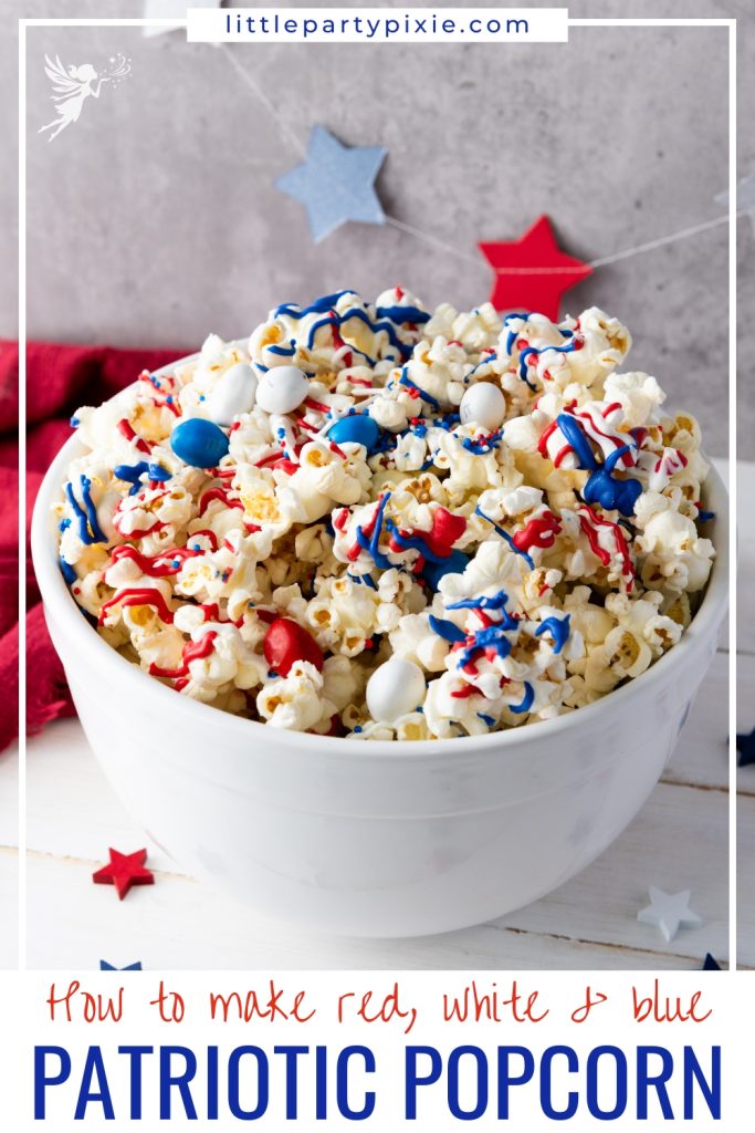 White bowl filled with red white and blue patriotic popcorn decorated with candy drizzle, M&Ms, and sprinkles with star decorations.