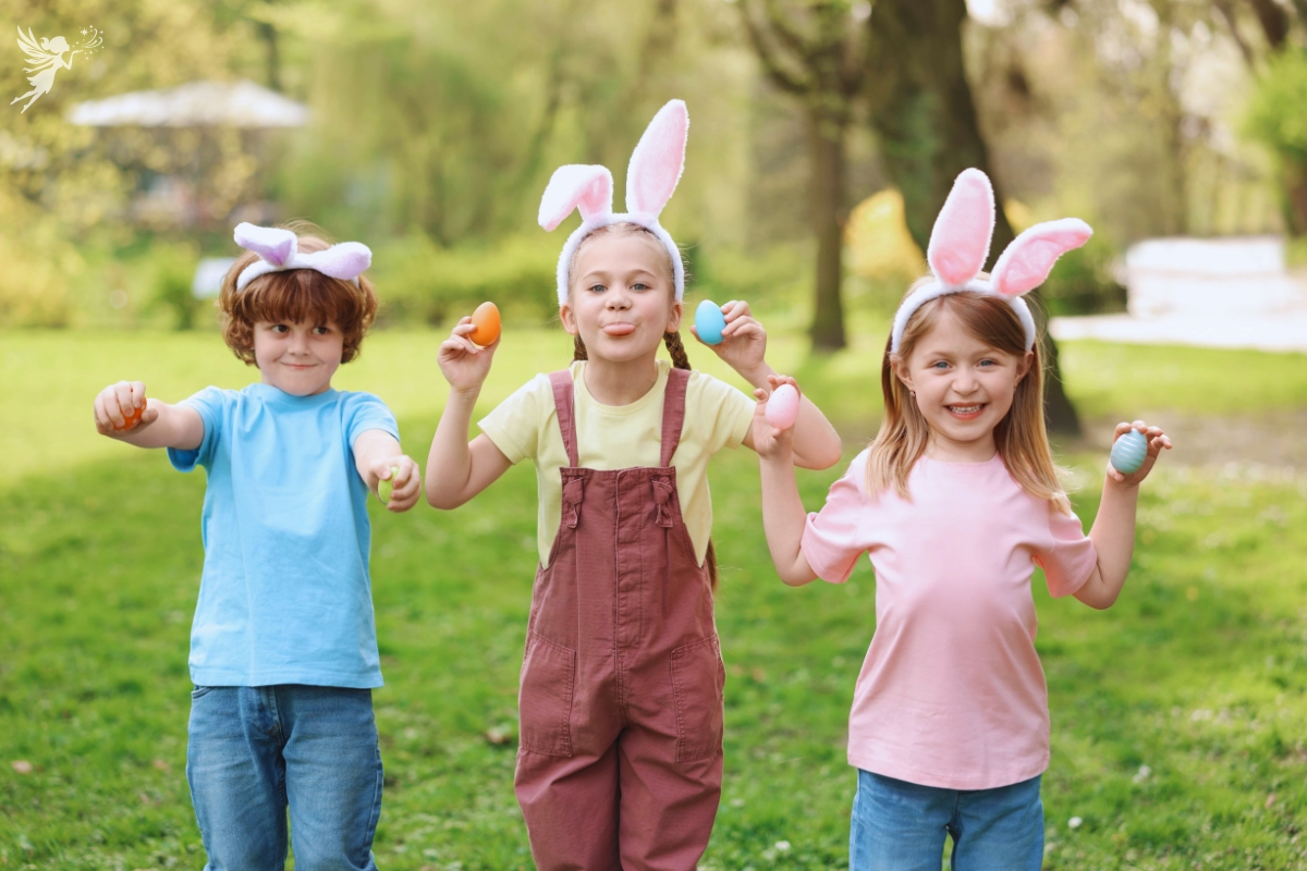 Easter Egg Hunt three children outside in bright green garden holding waster eggs wearing bunny ears
