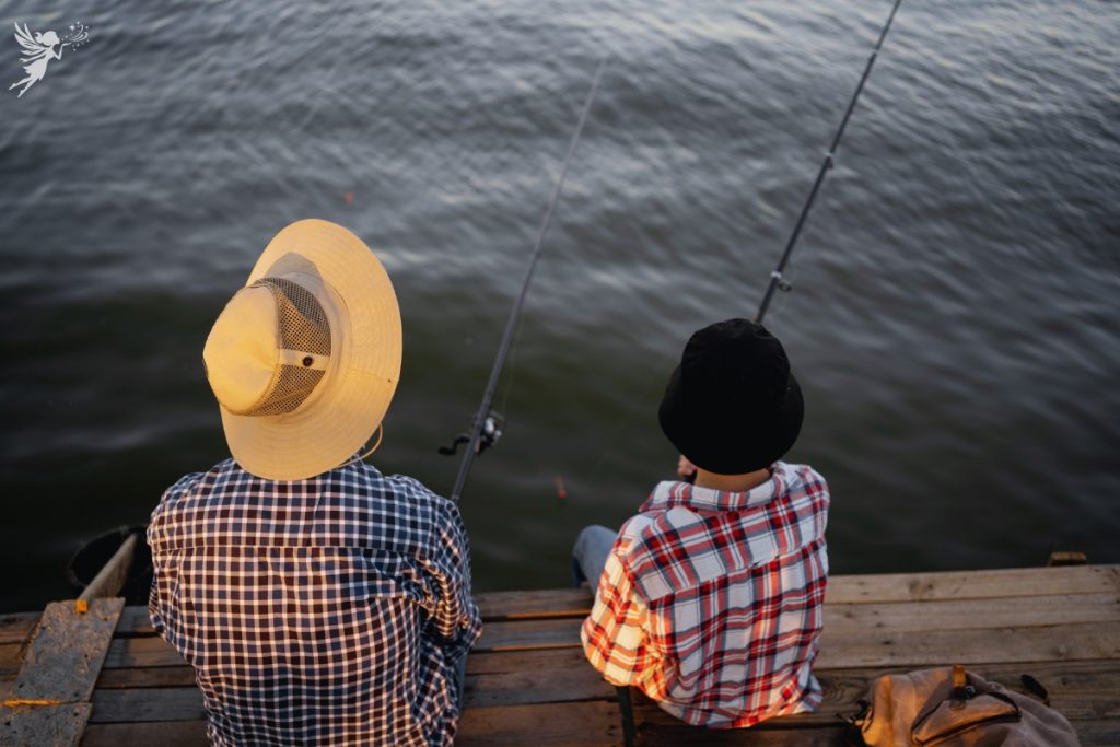father and son from behind with legs dangling over a pier fishing