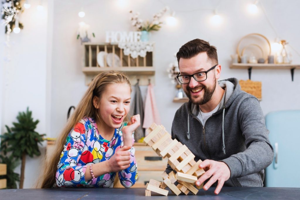father and tween daughter playing a jenga game laughing