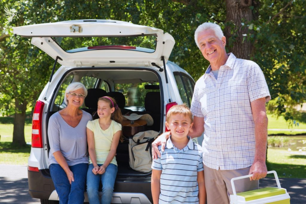 grand parents and children outside and SUV depicting a multigenerational family road trip