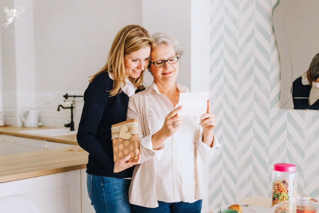adult woman giving her mom a gift envelope
