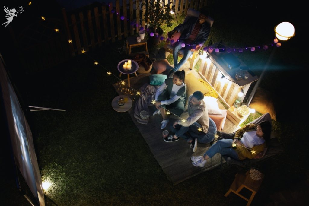 overhead view of adults sittingin a garden watching a movie projector screen