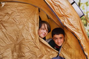boys sticking their heads out of a beige brown tent