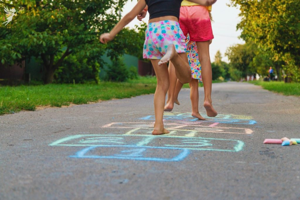 kids jumping in a chalk drawn hopscotch pathway
