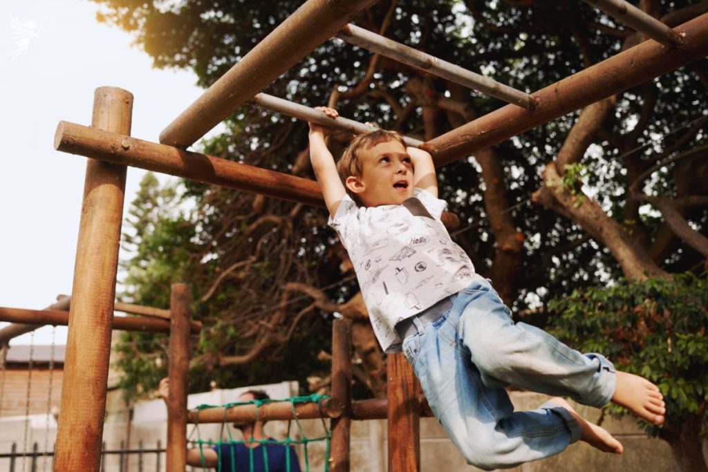 child on monkey bars in a backyard obstacle course challenge summer party idea for kids