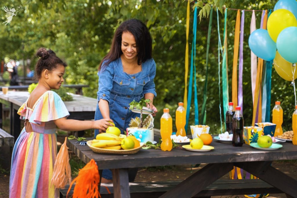 mother and daughter setting up a party table on a picnic bench in the park