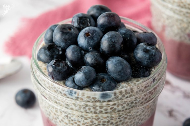 Close up of a blueberry chia pudding cup generously topped with fresh whole blueberries resting on a creamy chia seed layer.