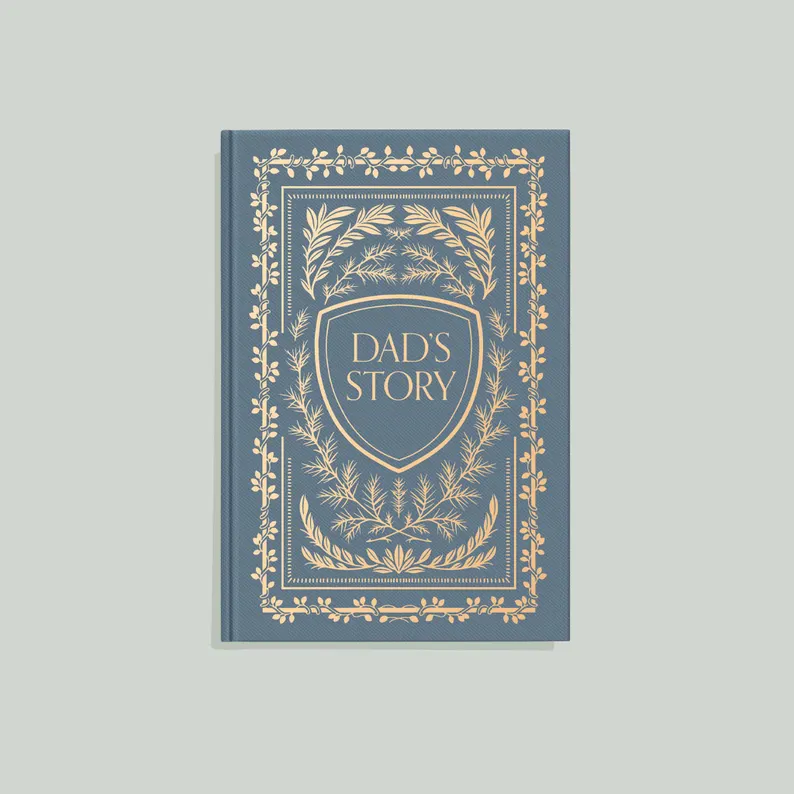 A classic blue and gold hardcover journal titled "Dad's Story" with elegant botanical details, making a thoughtful first Father's Day gift idea for new fathers. Etsy