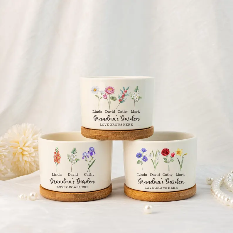 White ceramic plant pots with birth flower illustrations and personalized names, thoughtful mom sentimental gifts with bamboo saucers displayed together. Etsy