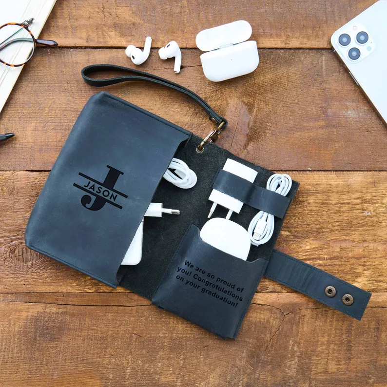 Open dark leather tech organizer personalized with the name Jason, holding charging cables and accessories, making it one of the most practical graduation gifts. Etsy