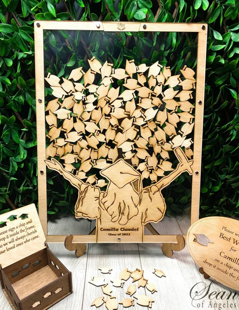 Wooden drop-top guest book frame shaped like a graduating figure filled with engraved cap shaped chips for signatures, a keepsake among graduation gifts. Etsy