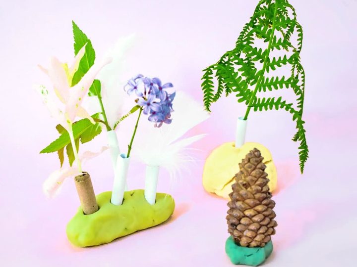 A nature-inspired fairy forest scene built with playdough, paper straws, flowers, and pine cones for fairy party crafts and activities.