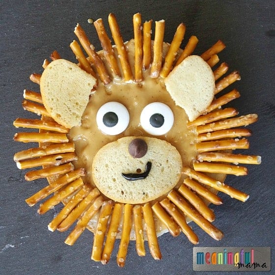Bagel lion face made with peanut butter and pretzel sticks, a creative safari animal party food idea for kids
