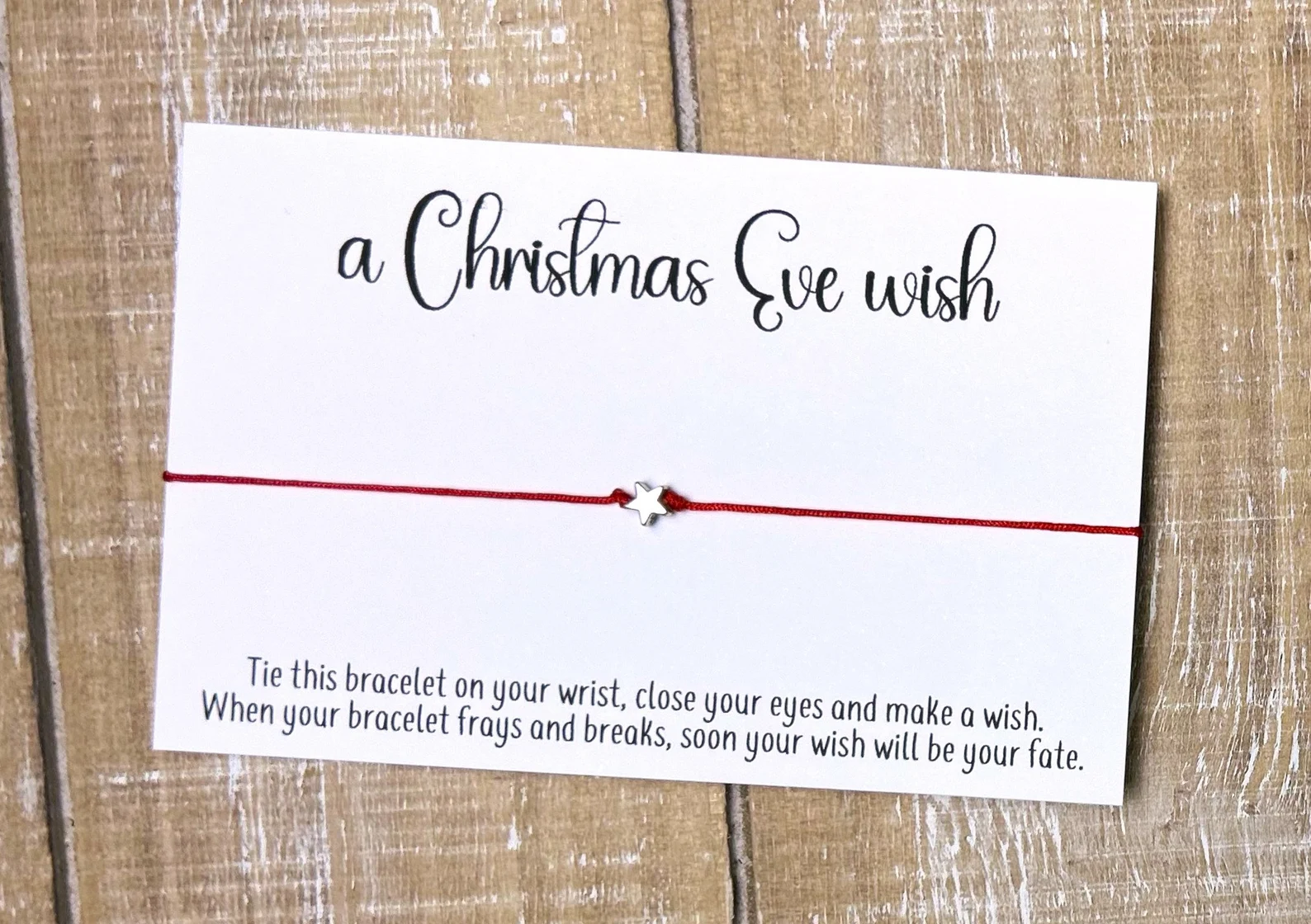 Red string wish bracelet with a silver star charm on a 'Christmas Eve Wish' card โ a magical and meaningful Christmas Eve box addition for teens.