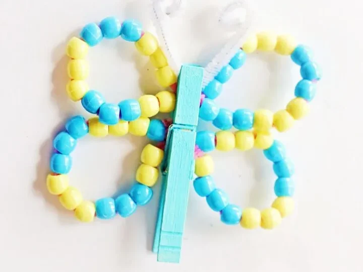A pretty butterfly craft made from a painted clothespin and colorful beads, a quick and easy fairy party crafts and activities idea.