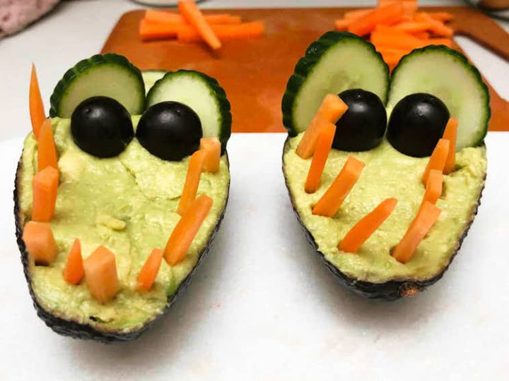 Avocado crocodile veggie dip with olive eyes and carrot teeth, a healthy safari animal party food idea