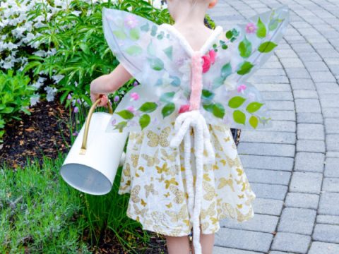A young girl wearing beautiful handmade flower butterfly wings outdoors, a magical fairy party crafts and activities idea guests can wear.
