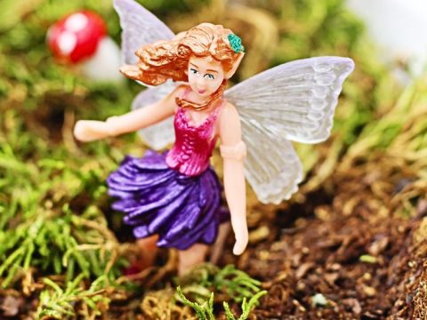A fairy figurine standing in a mossy sensory bin, an enchanting and easy fairy party crafts and activities setup for little ones.