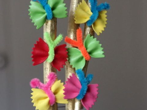 Colorful bowtie pasta butterflies attached to gold-painted sticks, a creative and playful fairy party crafts and activities wand idea.