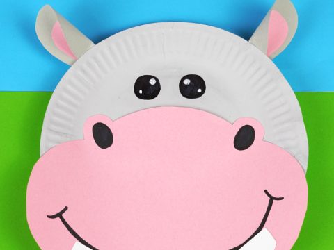 Smiling paper plate hippo craft with pink snout and gray ears for safari party crafts and activities