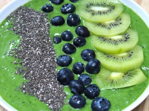 Vibrant green smoothie bowl topped with kiwi slices, blueberries, and chia seeds, a healthy jungle safari animal party food idea